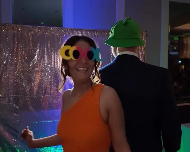 Guest in an orange dress wearing COOL novelty glasses on the booth
