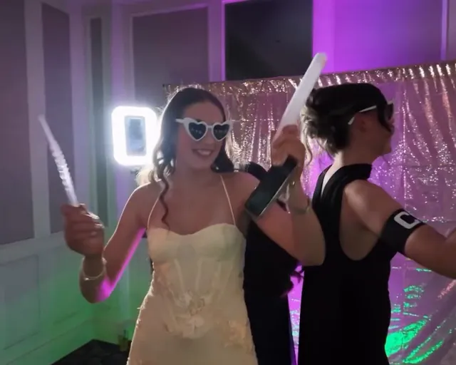 Two friends in heart sunglasses waving light-up sticks